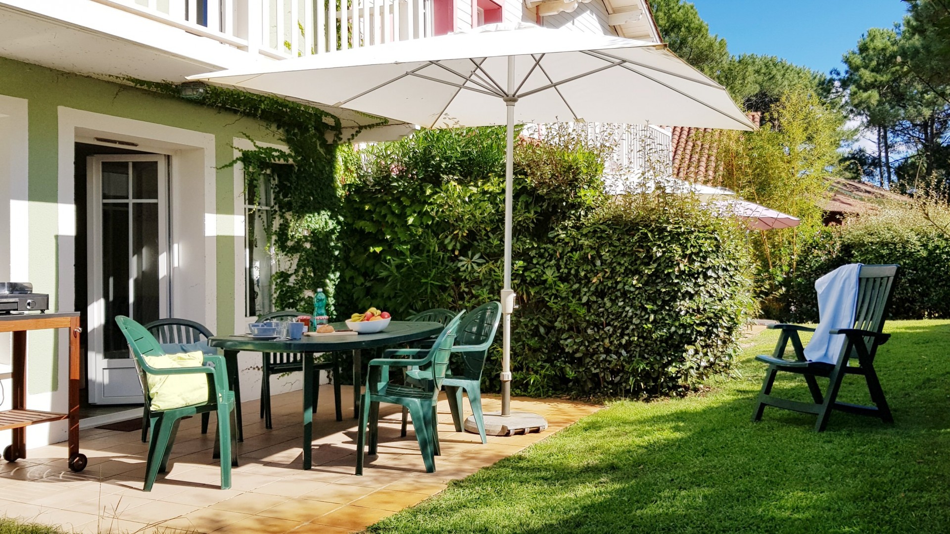 Agréable terrasse ensoleillée avec salon de jardin et plancha